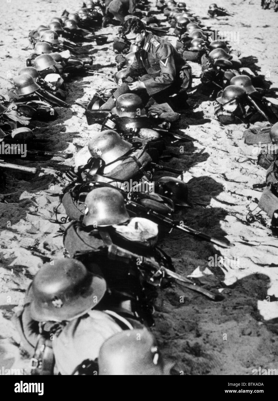 Nazi-Deutschland, ein deutscher Soldat Inspektion Stahl Helme und andere Geräte für die Wehrmacht (Streitkräfte) in Vorbereitung Stockfoto