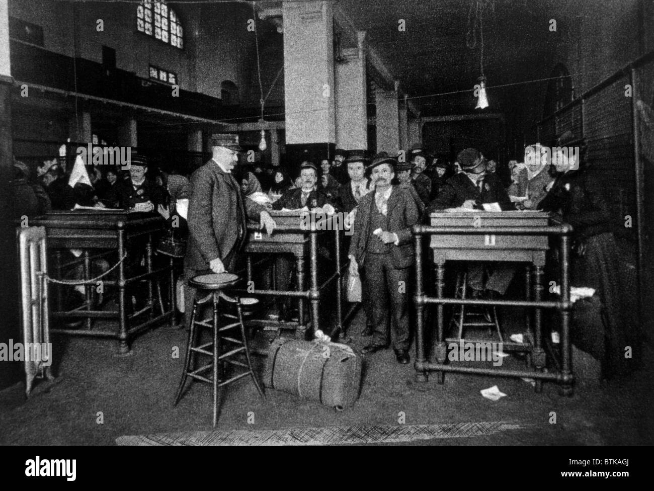 Eine Gruppe von Einwanderern zeigt Pässe, Geld, und Beantwortung von Fragen vor der endgültigen Freilassung in den Vereinigten Staaten, Ellis Island, c. 1902. Stockfoto