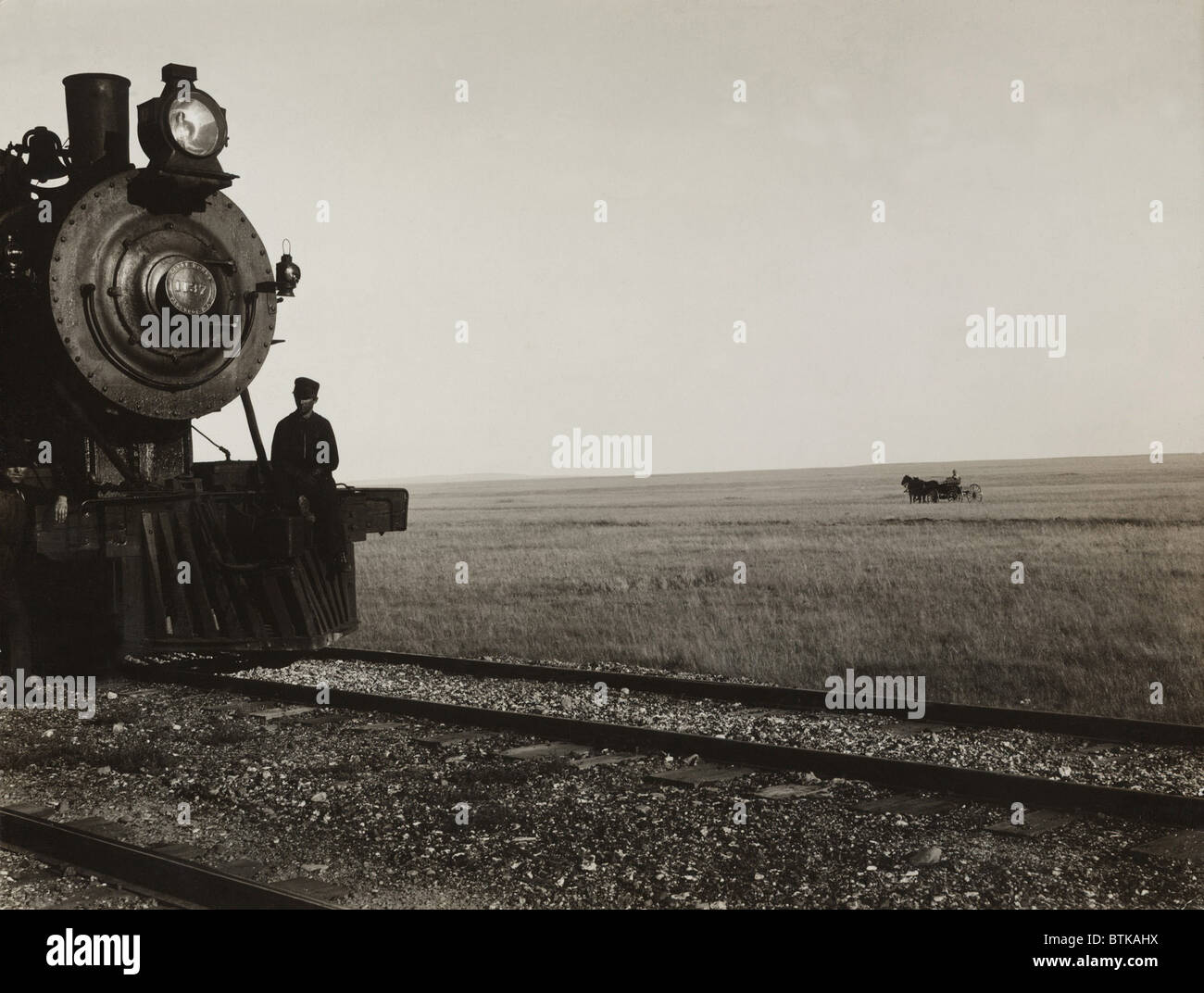 Zwei Männer stehen auf der Kuh-Fänger einer Great Northern Railroad-Lokomotive auf der Montana-Prärie. In der grüne Hintergrund ist Stockfoto