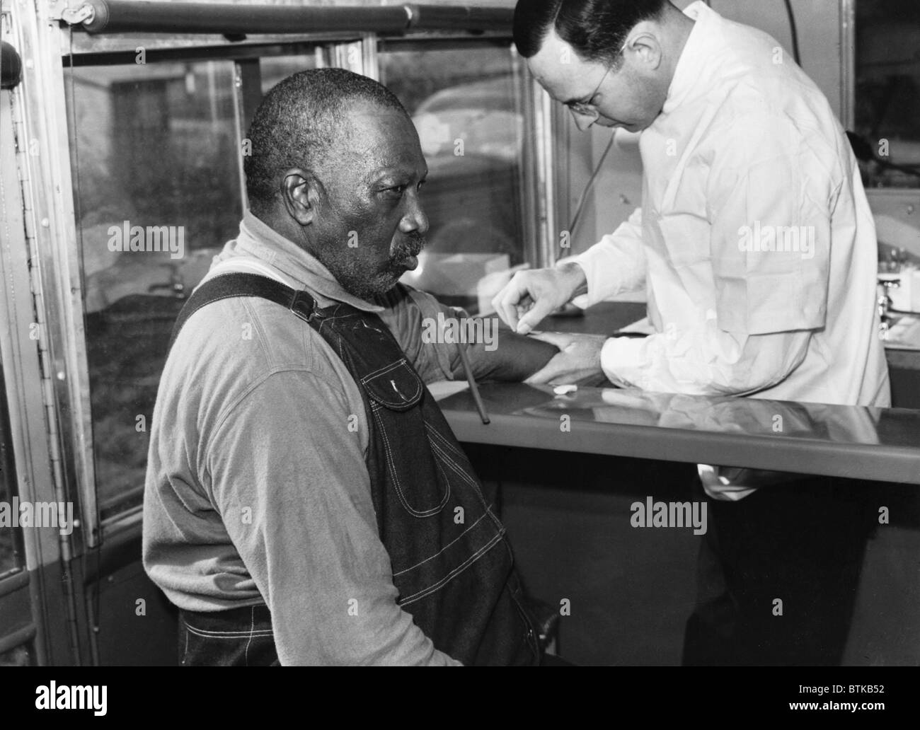 Afroamerikanische Patienten Behandlung für Syphilis in Public Health Service Klinik auf Rädern, Wadesboro, N.C. in den 1930er Jahren. Behandlungen für Syphilis war bis die Verfügbarkeit von Penicillin in den 1940er Jahren das potenziell giftige Arsen-haltige Medikament Salvarsan. Stockfoto