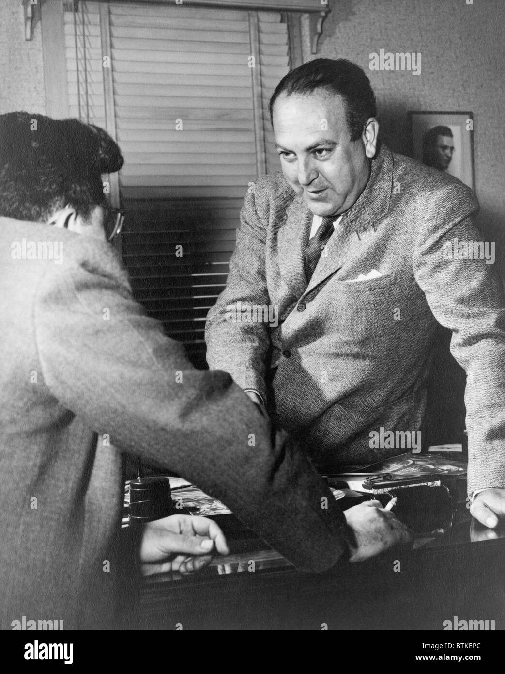 Regisseur Robert Wise (1914-2005) und Produzent Val Lewton (links) im Gespräch über einen Schreibtisch.  Lewton wurde Leiter des Referats B-horror Stockfoto