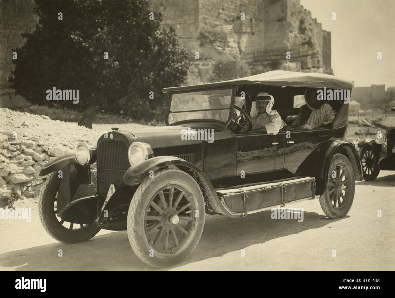 Arabische Männer tragen traditionelle Keffiyeh in einem PKW in den 1920er Jahren. Auf dem Trittbrett sind Tanks, Treibstofftanks für Reisen in Gebiete ohne Tankstellen, Stockfoto