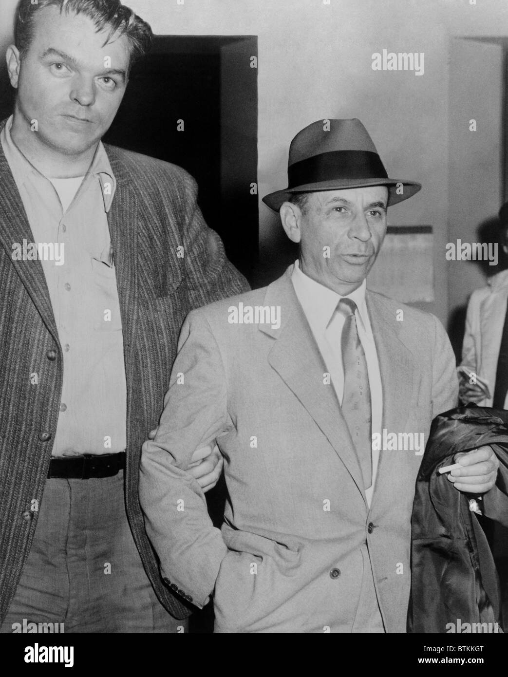Glücksspiel-Chef Meyer Lansky (1902 – 1983), unter der Leitung von einem Detektiv für die Buchung bei Landstreicherei Aufladung Polizeistation 54th Street, New York City, 13. Februar 1958. Stockfoto