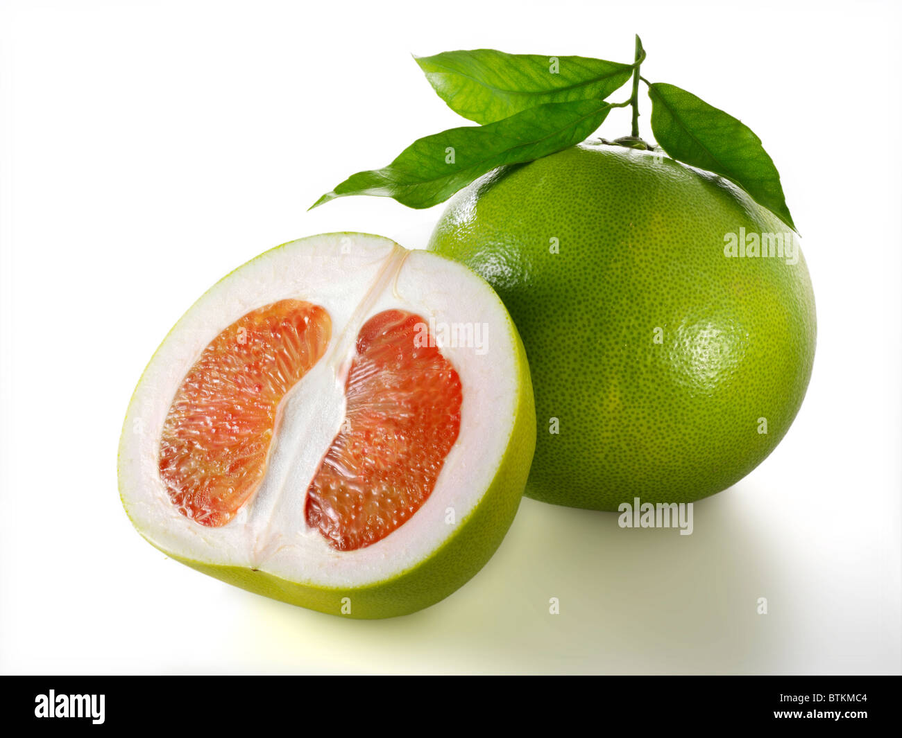 Frische ganze und geschnittene Pomelo Zitrusfrüchte vor einem weißen Hintergrund Stockfoto