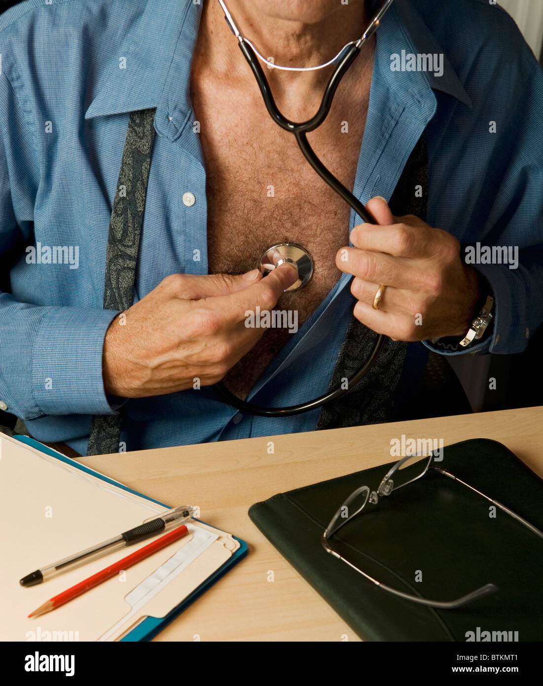Mann tut Selbstuntersuchung mit Stethoskop Stockfoto