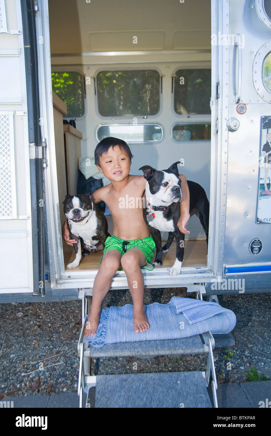 Junge sitzt in der Tür der Camper mit Hunden Stockfoto