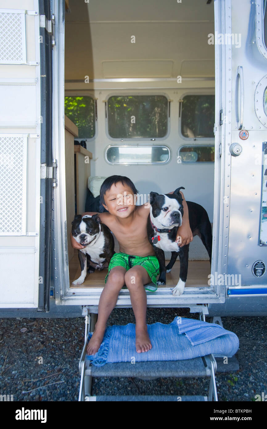 Junge sitzt in der Tür der Camper mit Hunden Stockfoto
