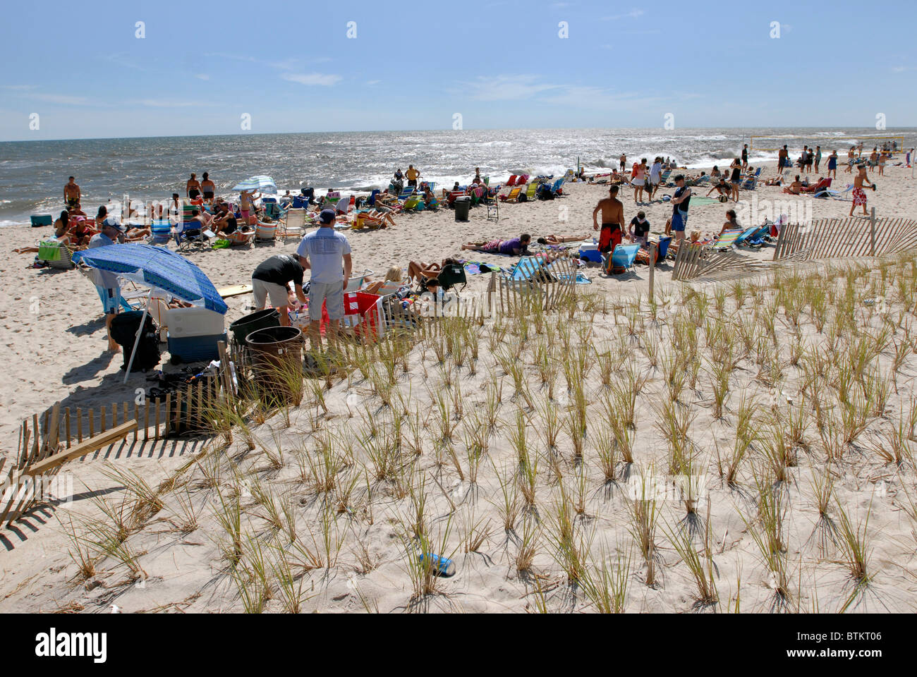 Ocean Bay Park Strand auf Fire Island New York mit Sonnenanbeter. Bepflanzte Dünengras schützt den Strand von atlantische Stürme. Stockfoto