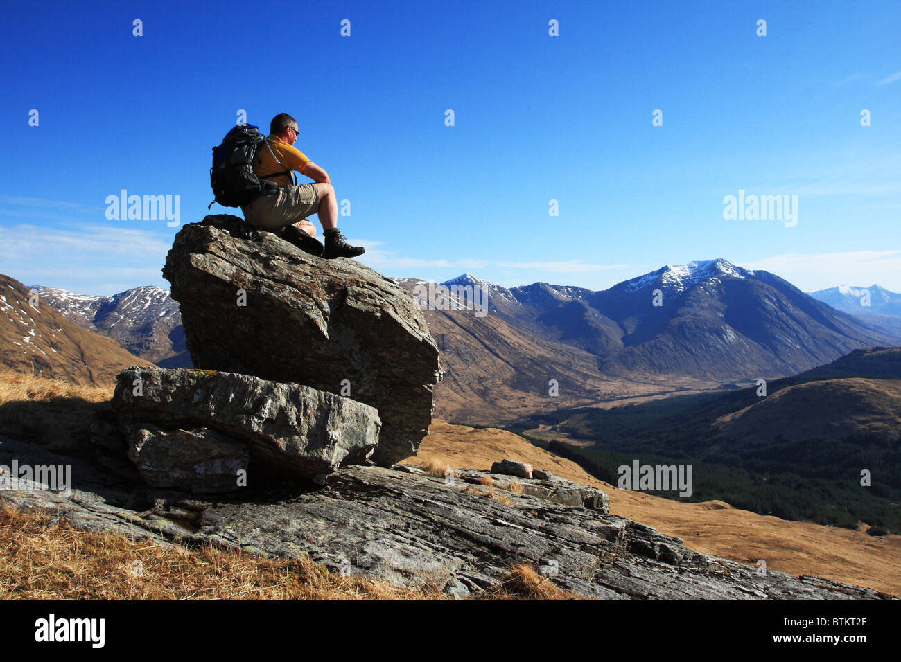 Hillwalker ruht auf einem Felsen und Blick über Glen Etive, Ben Starav. Stockfoto