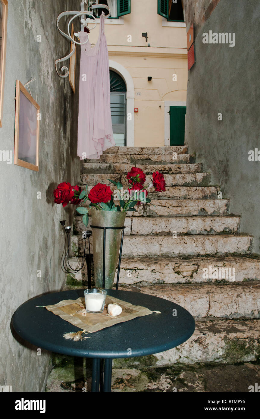 urige lokale Seitenstraße in Rovinj mit Stufen hinunter runder Tisch mit Rosen in Vase auf dem display Stockfoto