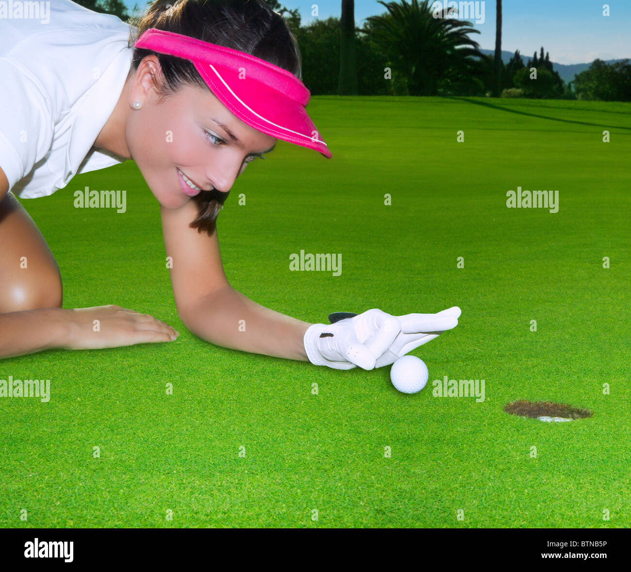 Grün Loch Kurs Frau Humor flicking hand eine Kugel im Inneren kurz Golf putt Stockfoto