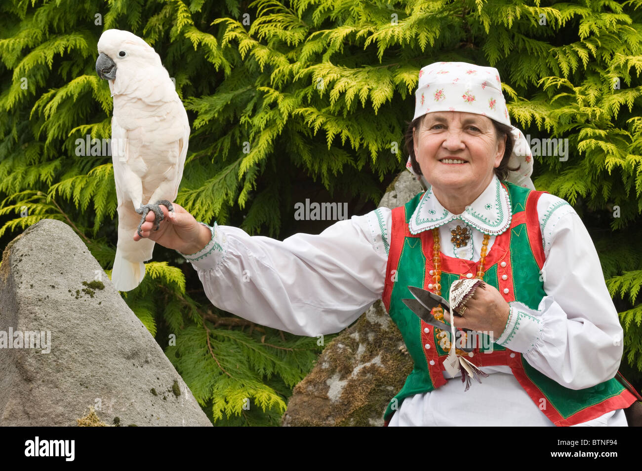 Apolonia Nowak polnischen Volkskünstler, tragen Tracht aus Kurpie Region, mit Lachs-crested Kakadu (Cacatua Moluccensis). Stockfoto