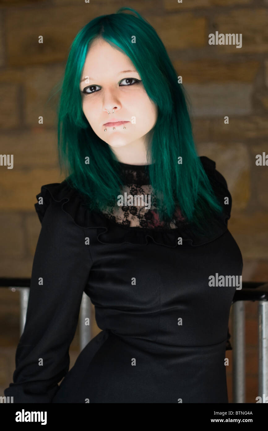 Ein Goth-Mädchen mit grünen Haaren trägt ein grünes Kleid und stehen in einer Feuertreppe. Stockfoto