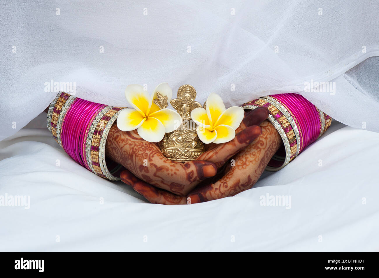 Indisches Mädchen tragen weiße Seide sari mit Henna hands holding eine Frangipani Blume und einer Statue von Ganesha. Indien Stockfoto