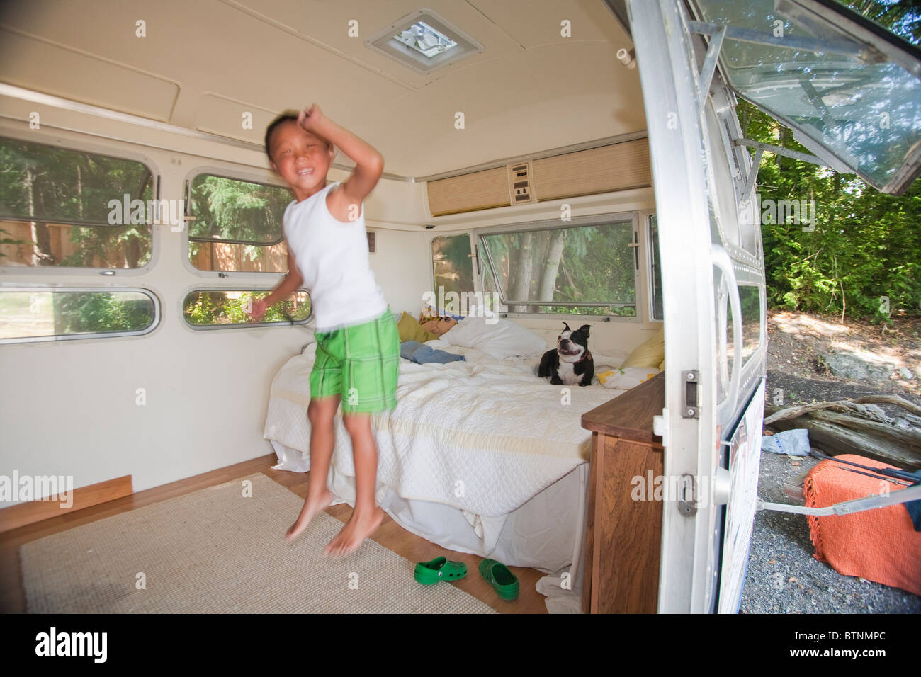 Junge und Hund im Bett im Wohnmobil Stockfoto
