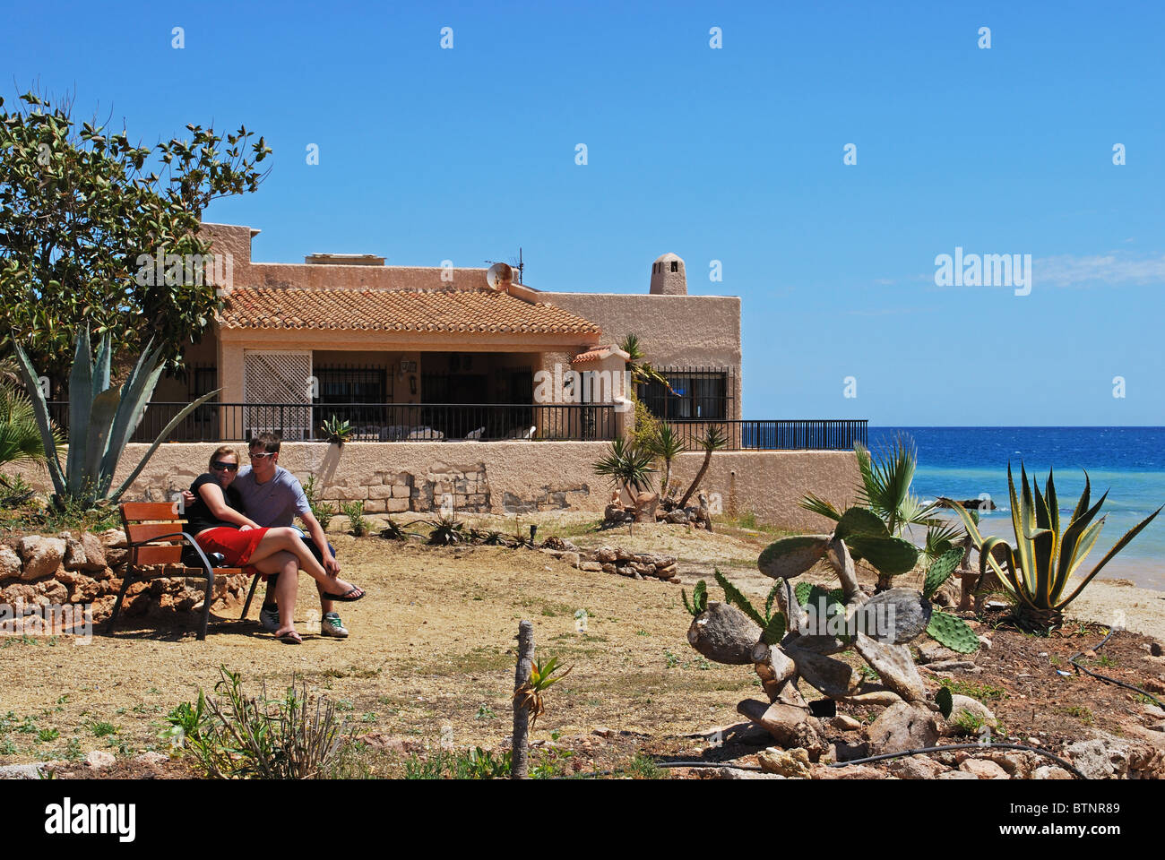 Paar auf einer Bank sitzend, am Rande des Strandes, Mojacar, Costa Almeria, Provinz Almeria, Andalusien, Südspanien, Westeuropa. Stockfoto