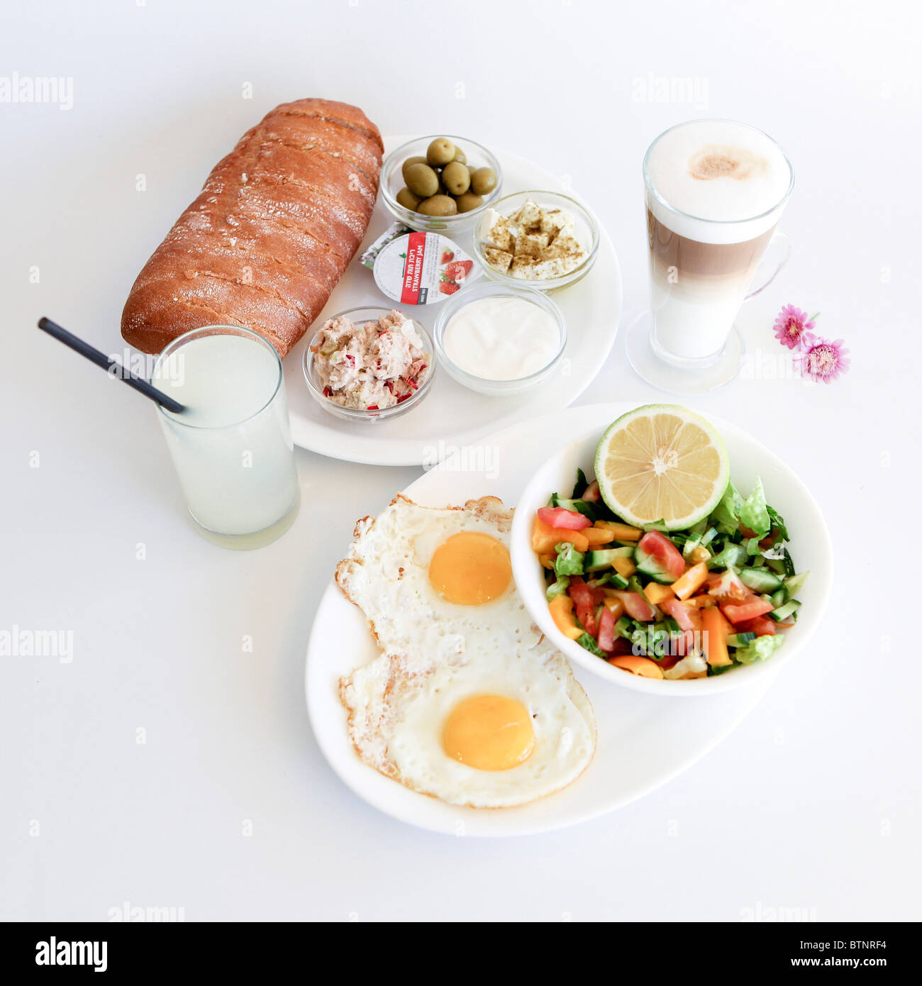 Traditionelle israelisches Frühstück mit zwei Spiegeleiern, gelben Käse, Salat, ein frisches Brötchen und eine Tasse cappuccino Stockfoto