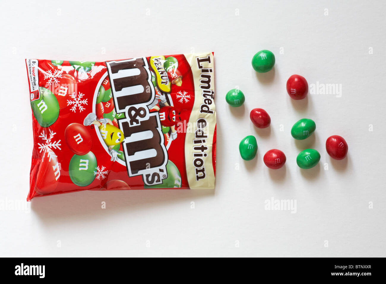 Geöffnete Paket der Special Limited Edition Weihnachten Erdnuss M&M's mit Inhalt verschüttet Verschüttete auf weißem Hintergrund Stockfoto