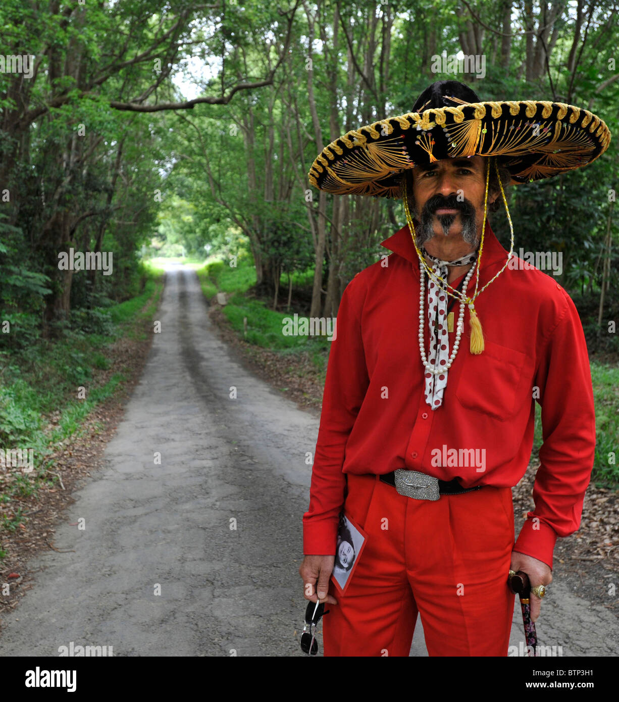 Ein elegant gekleideter Mann steht auf einer Straße, gekleidet in einen mexikanischen Sombrero Stockfoto