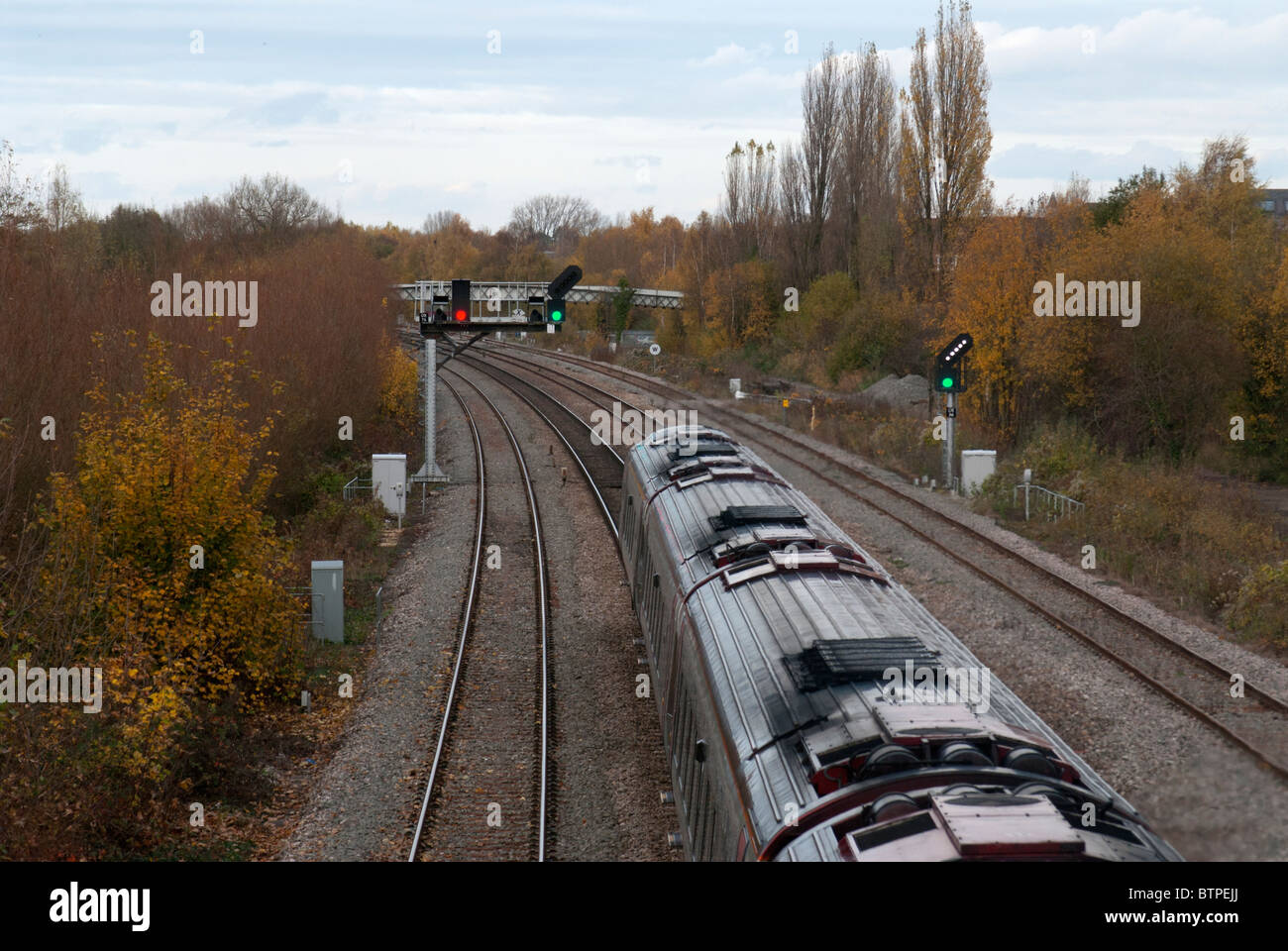 UK-Zug auf Schienen durch grünes Signal unterwegs Stockfoto