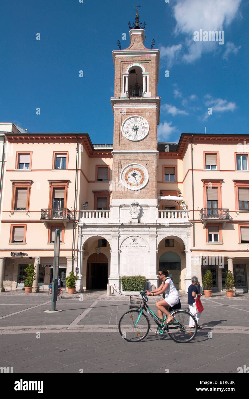 Frau Radfahren vorbei Uhrturm, Uhrzeit, Datum und Zodiac anmelden, Piazza Cavour, Rimini, Emilia Romagna, Italien Stockfoto