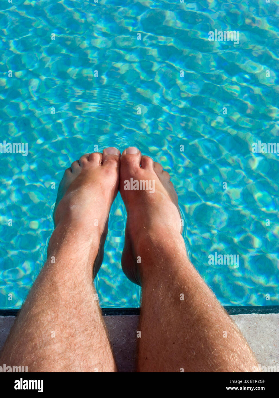 SELF PORTRAIT EINES MANNES, SEINE FÜßE EINWEICHEN, IN EINEM SCHWIMMBAD. Stockfoto