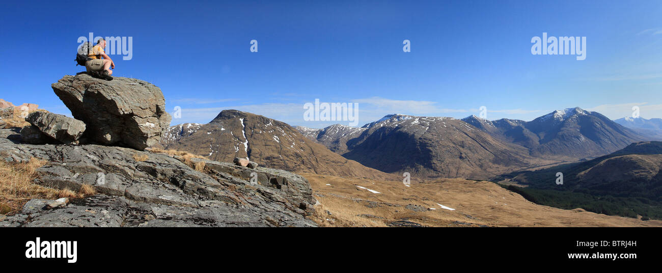 Hillwalker ruht auf einem Felsen und Blick über Glen Etive, Ben Starav. Stockfoto