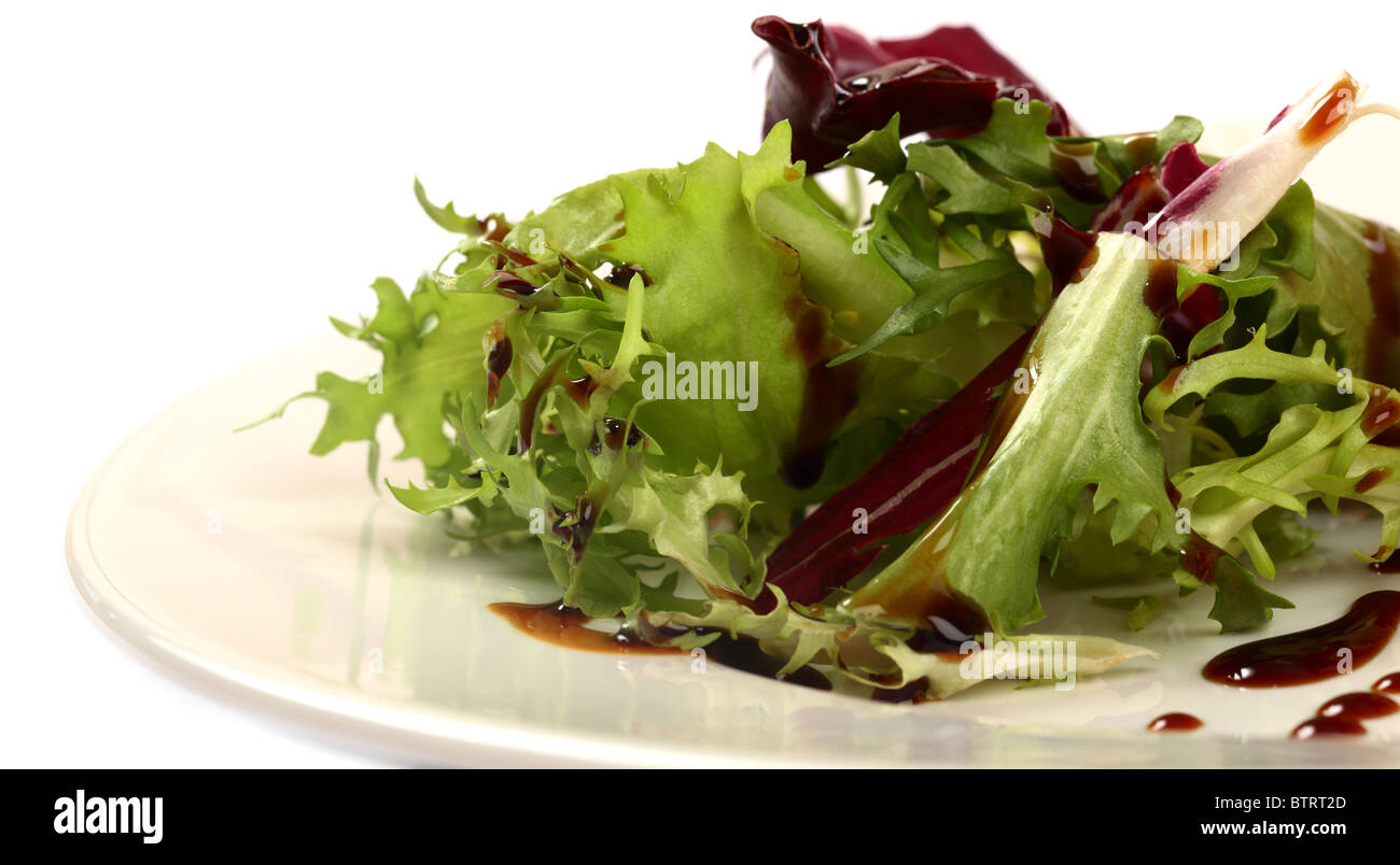 Grüner Salat mit Dressing auf einem weißen Teller Stockfoto