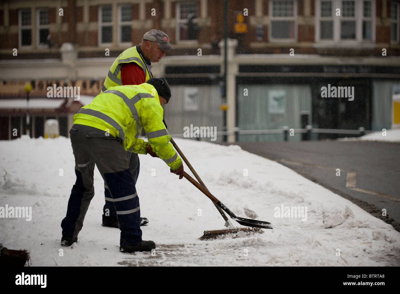 Kommunalbeschäftigten klar Schnee und Eis aus dem Bürgersteig. Stockfoto