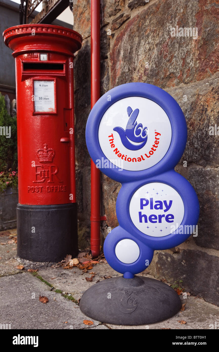 Die Nationale Lotterie spielen hier' Zeichen außerhalb einer Post mit britischen Briefkasten. Großbritannien, Großbritannien. Stockfoto