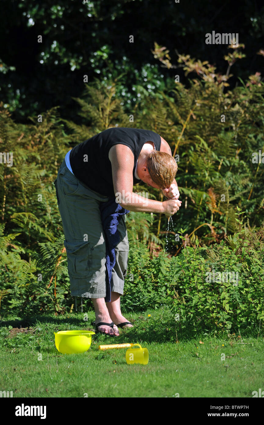 Eine Frau wäscht ihre Haare außerhalb in einem camping-Ausflug Stockfoto
