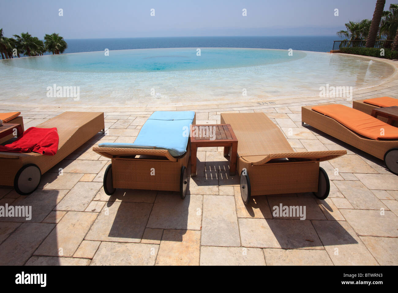Liegestühle in der Nähe eines Schwimmbads mit dem Meer im Hintergrund Stockfoto