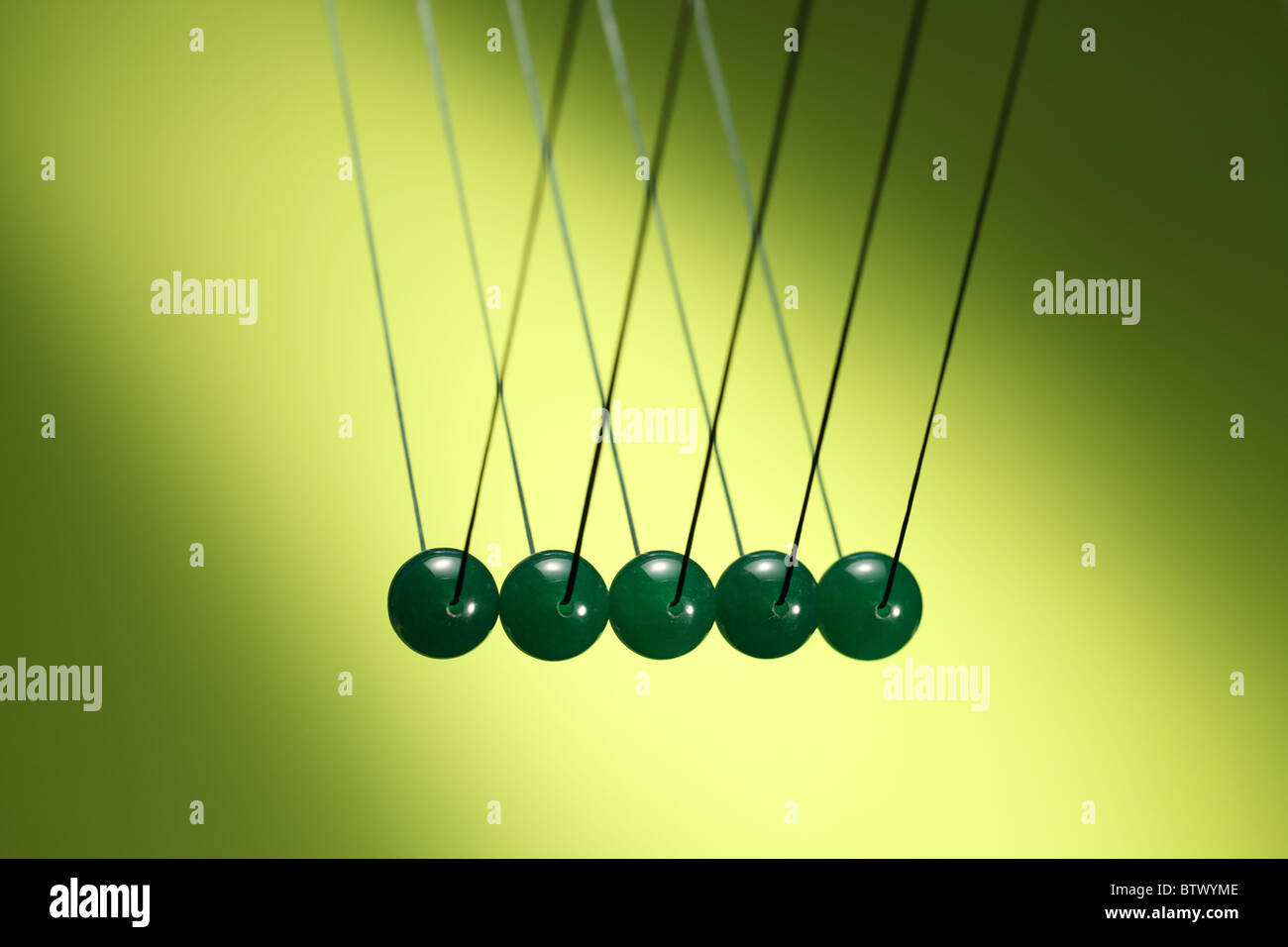 Fünf grüne Murmeln in Reihe von Schnur hängen. Zeigt Newtons Wiege, ein Gerät, das der Impulserhaltung demonstriert. Stockfoto