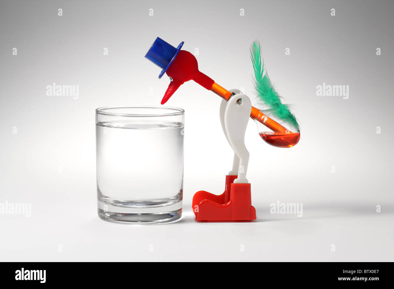 Ein Spielzeug-Vogel, trinken aus einem Glas Wasser Stockfoto