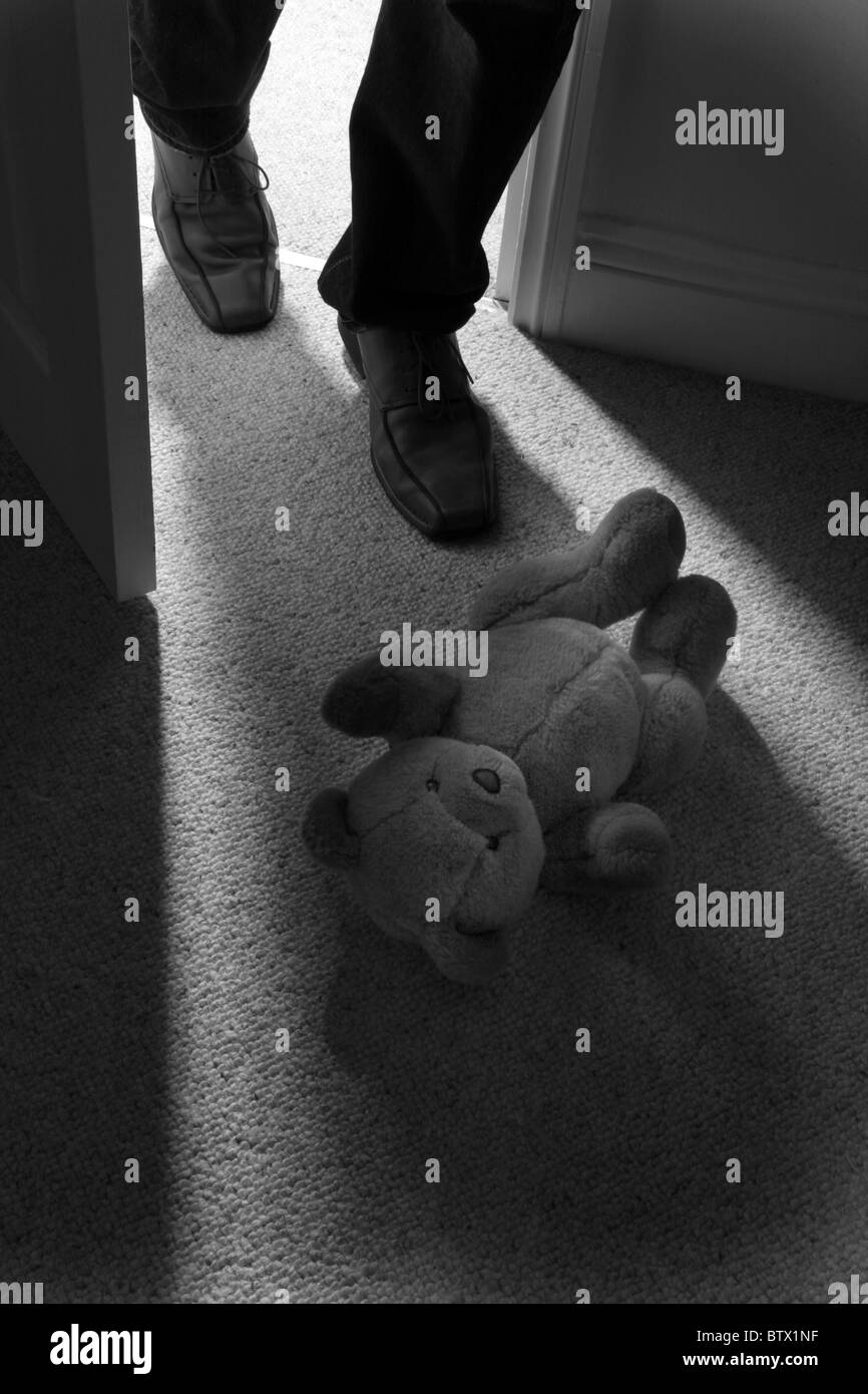 Beine und Carbonrigg treten hinter ein Kind Teddy Mannes tragen auf den Boden, um den Raum zu verlassen. Stockfoto