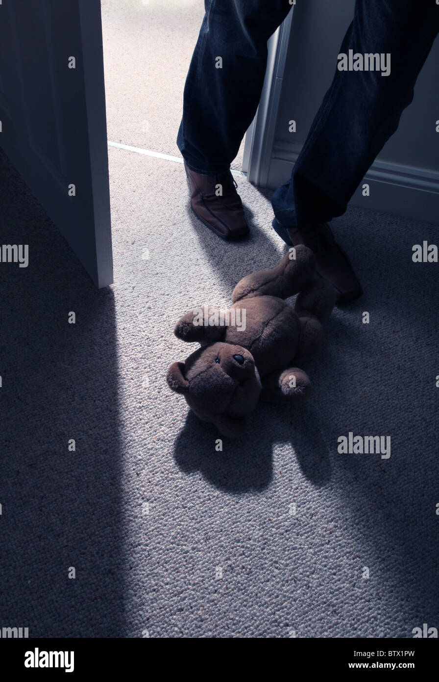 Beine und Carbonrigg treten hinter ein Kind Teddy Mannes tragen auf den Boden, um den Raum zu verlassen. Stockfoto