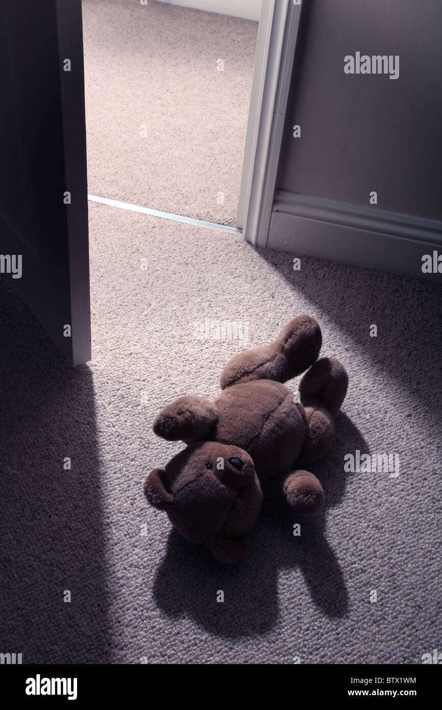 Beine und Carbonrigg treten hinter ein Kind Teddy Mannes tragen auf den Boden, um den Raum zu verlassen. Stockfoto