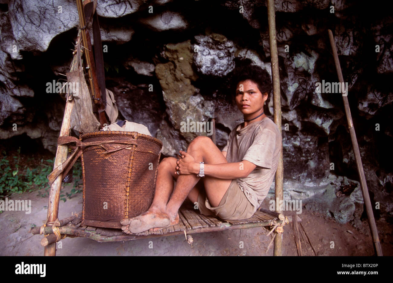 Ein Bodenbauern Batu Mann mit einem Luftgewehr und seinen gesamten Besitz auf der Plattform, wo er in einer Höhle im Süden der Philippinen lebt. Stockfoto