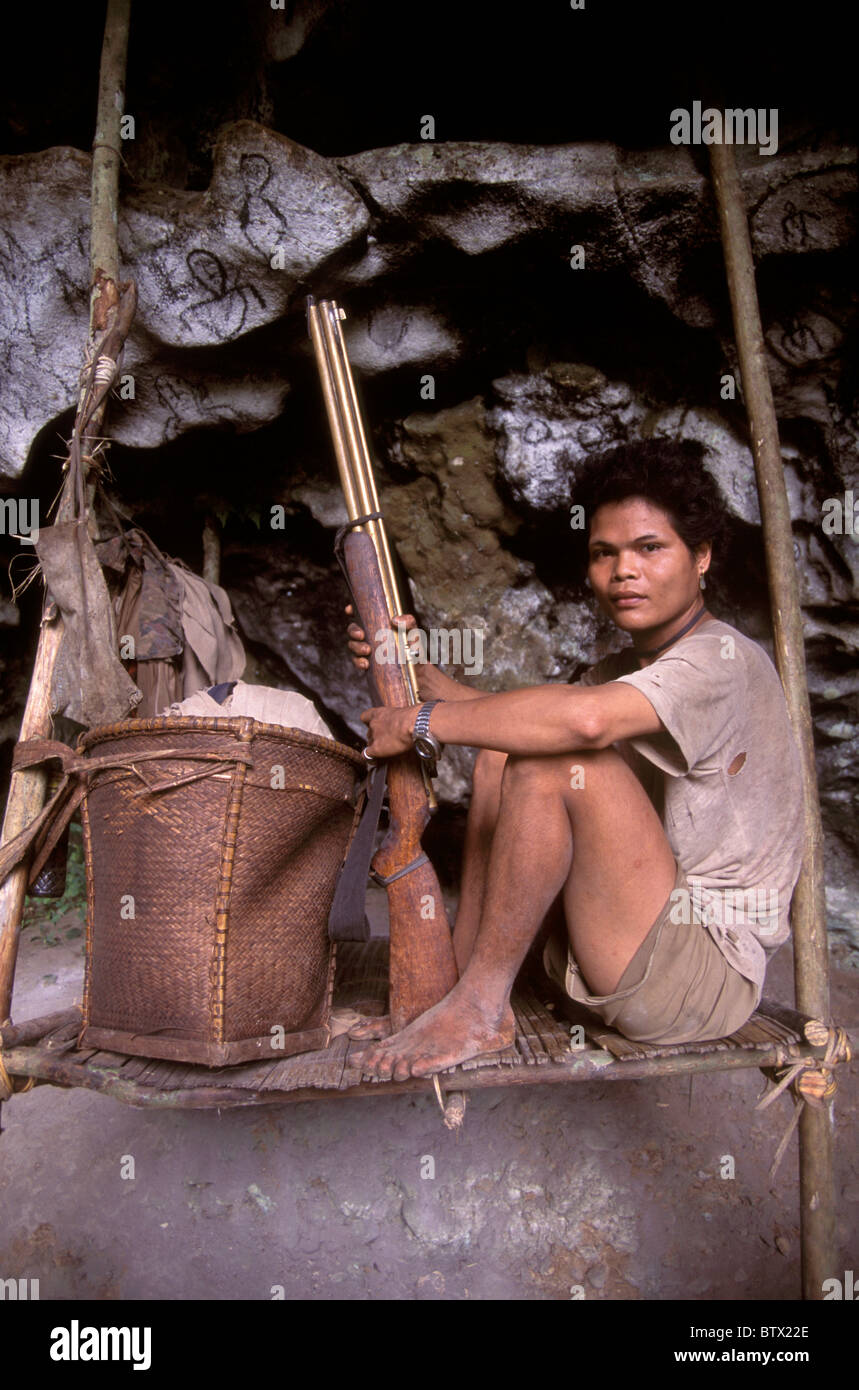 Ein Bodenbauern Batu Mann mit einem Luftgewehr und seinen gesamten Besitz auf der Plattform, wo er in einer Höhle im Süden der Philippinen lebt. Stockfoto
