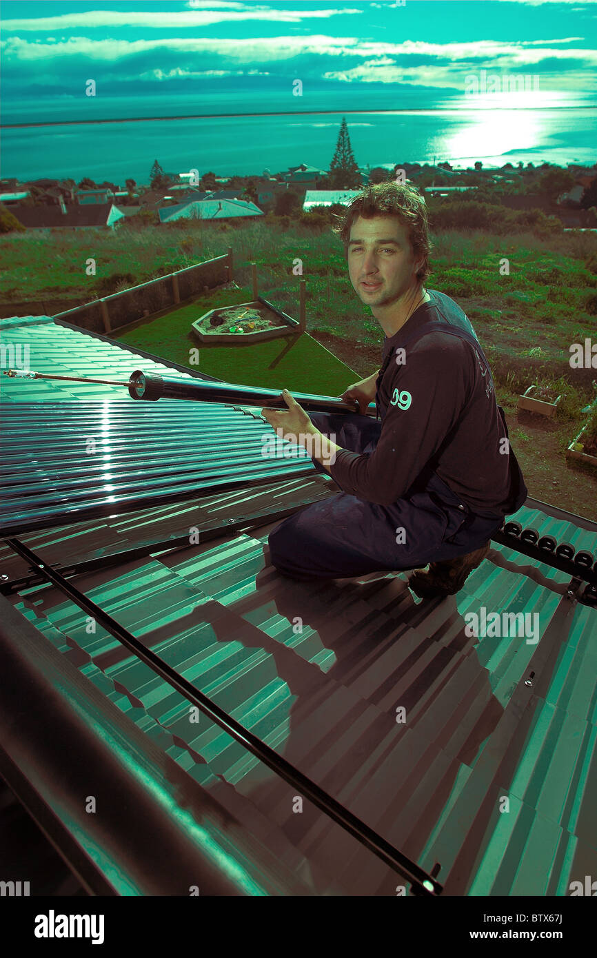 Qualifizierte Handwerker, die Installation von solar-Warmwasser-System zu einem Haus, Nelson, New Zealand, die Stadt mit der höchsten Sonnenstunden. Stockfoto