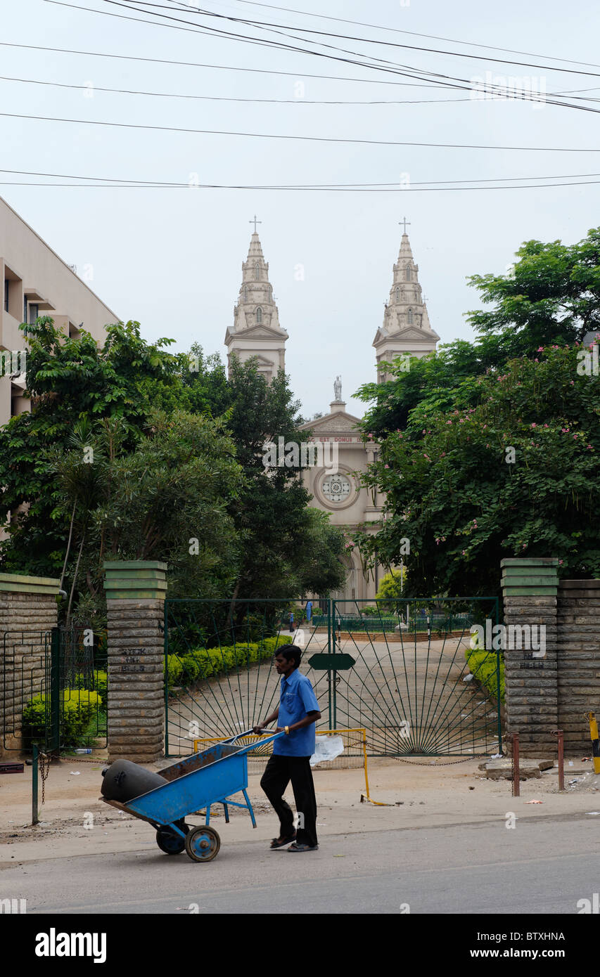 Ein Mann, Schubkarre vorbei an St. Patricks Kathedrale in Bangalore. Dies ist der primäre katholischen Ort der Anbetung in der Stadt. Stockfoto