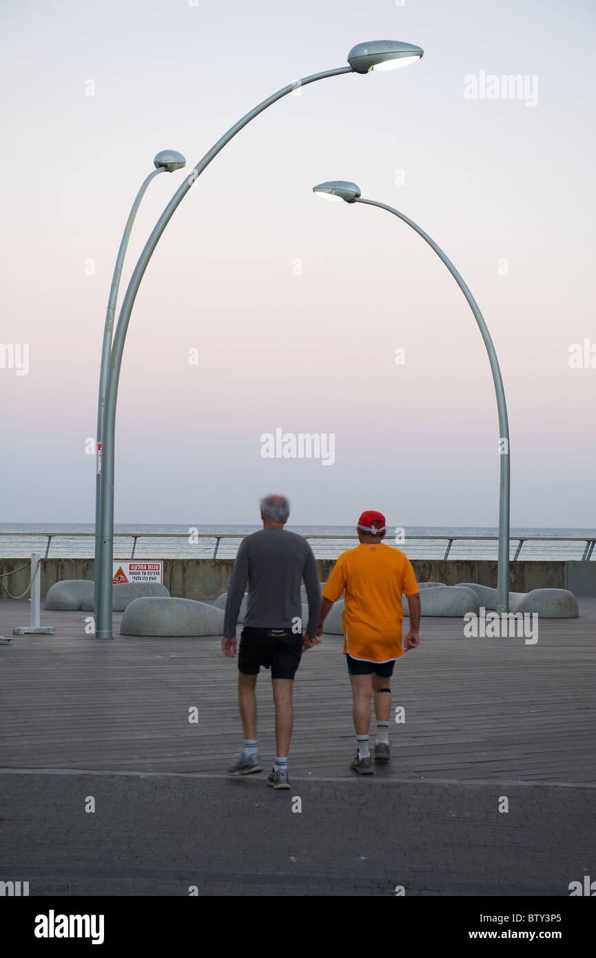 Zwei Mann zu Fuß auf Tel-Avivs Strandpromenade bei Sonnenaufgang. Stockfoto