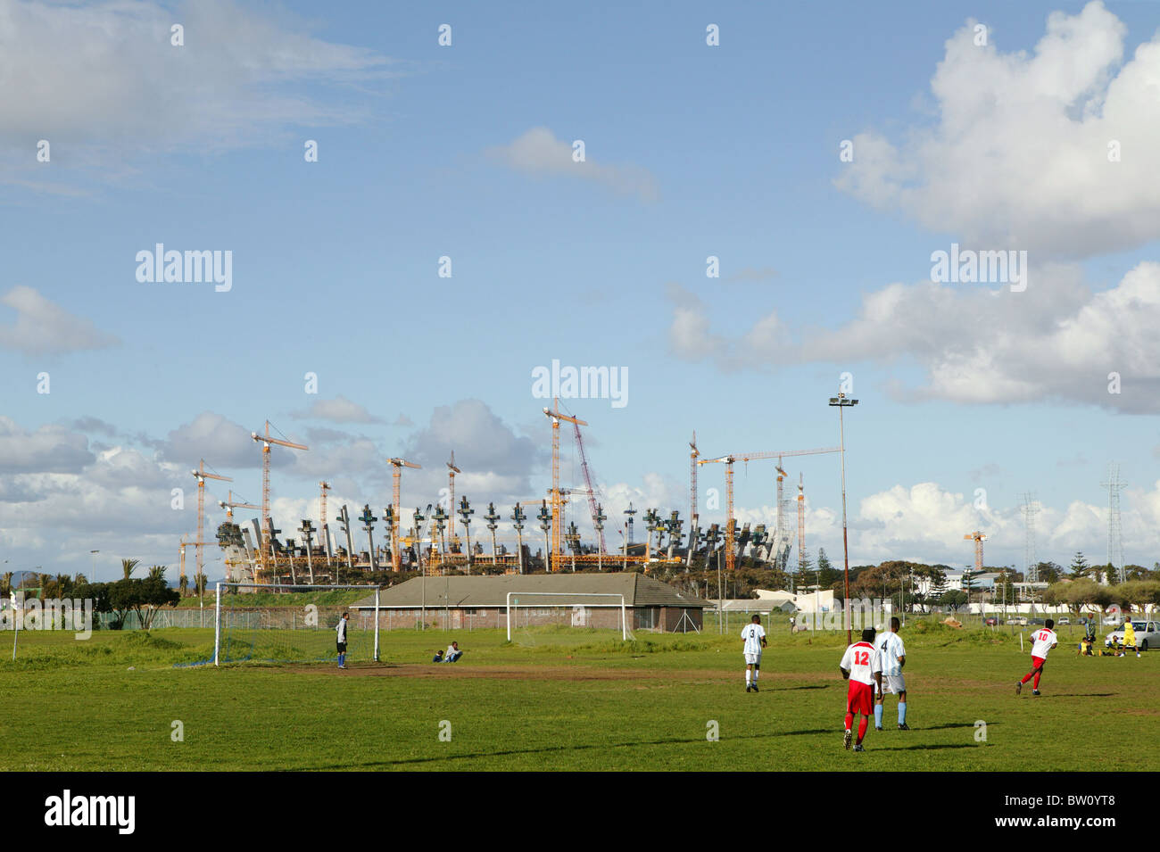 Blick auf das Green Point Stadion im Bau, mit einem lokalen Fußballspiel im Gange im Vordergrund Stockfoto