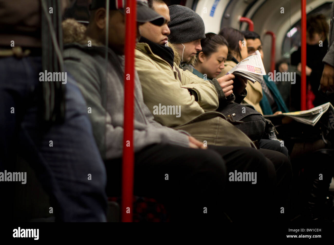 Londoner u-Bahn Reisende Passagiere Pendler, mit Mann Metro Zeitung lesen Stockfoto