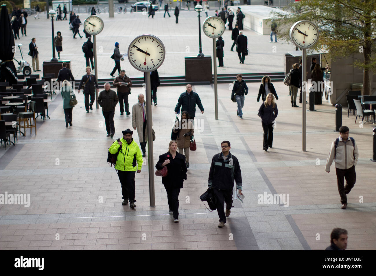 Uhren außerhalb Canary wharf Station mit Stadtarbeiter, sechs öffentliche Uhren, Konstantin Grcic, Skulptur, Stahl, Glas Stockfoto