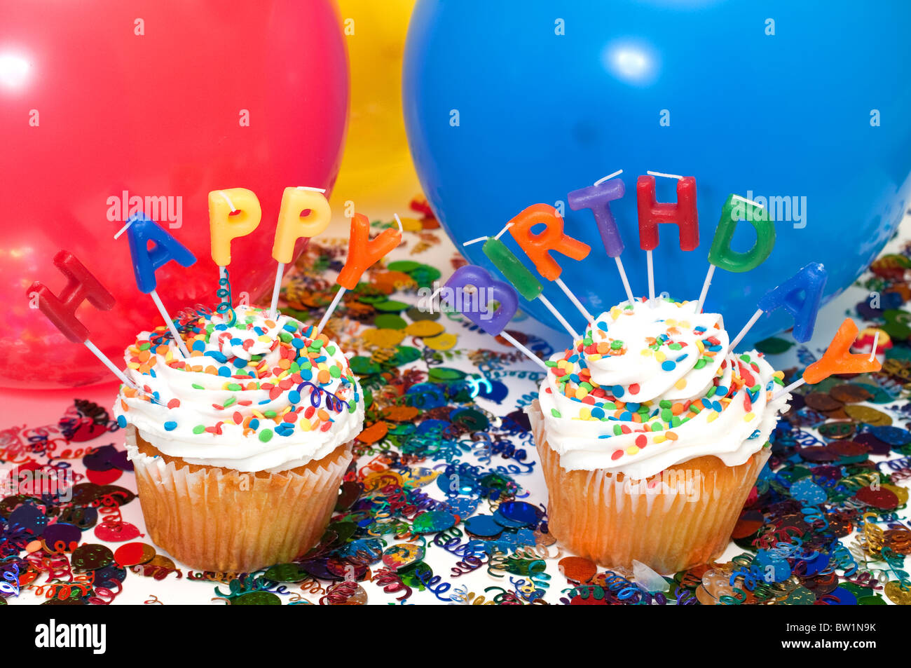 Geburtstagsfeier mit Muffins, Kerzen, Luftballons und Konfetti. Stockfoto