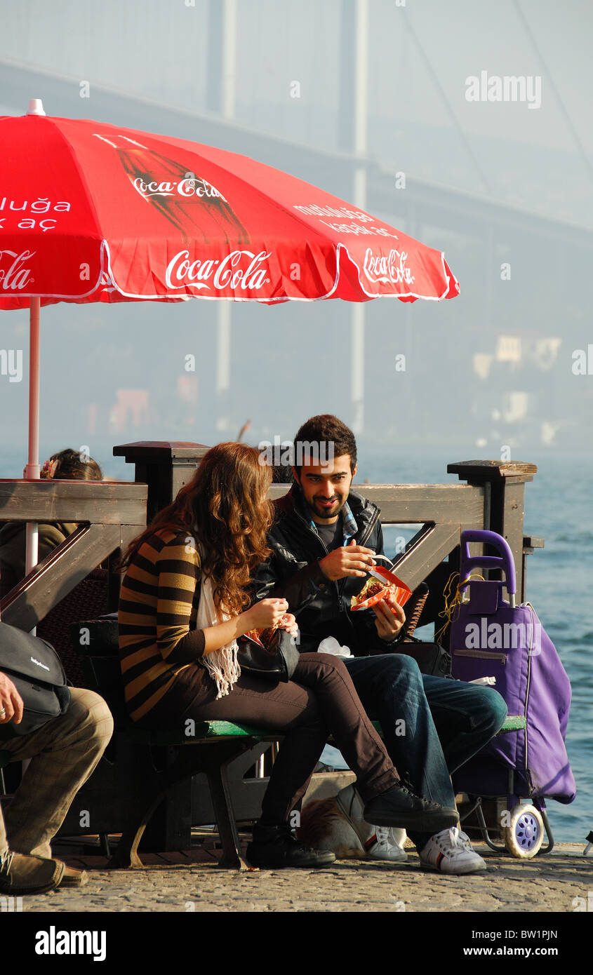 ISTANBUL, TÜRKEI. Ein junges türkisches Paar Imbiss essen durch den Bosporus in Ortakoy Markt, Besiktas Bezirk. 2010. Stockfoto