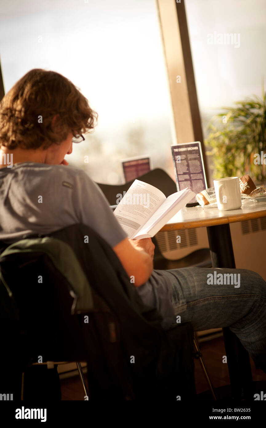 Ein Schüler liest ein Lehrbuch im Café der Aberystwyth University Wales UK Stockfoto