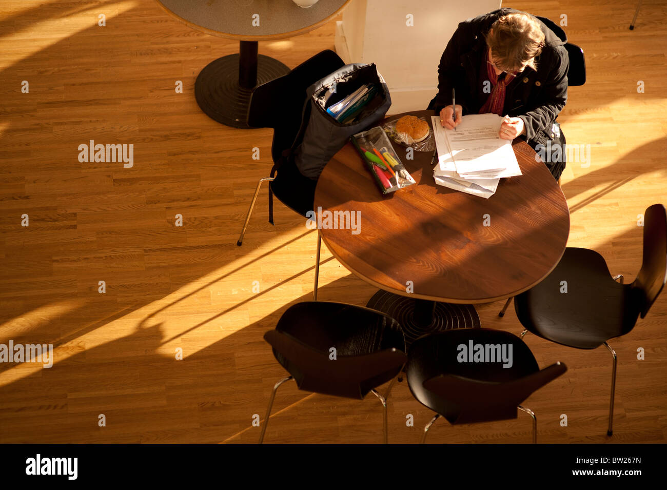 Draufsicht nach unten auf eine studentische Arbeit schreiben sitzt an einem Tisch im Café der Aberystwyth University Wales UK Stockfoto