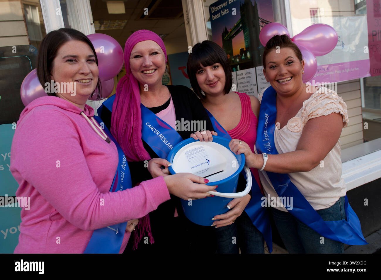 vier Frauen Shop Arbeiter freiwillige gekleidet in rosa sammeln Geld für die Krebsforschung, UK Stockfoto